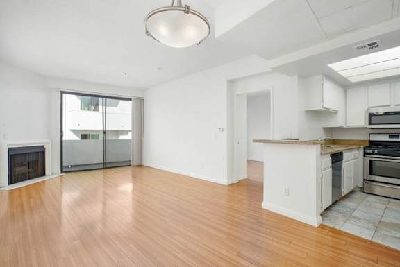 A spacious kitchen and living room with hardwood floors and white cabinetry.