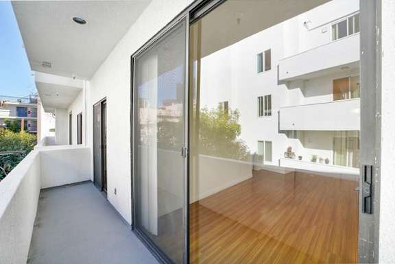A balcony with a glass door and a wooden floor.