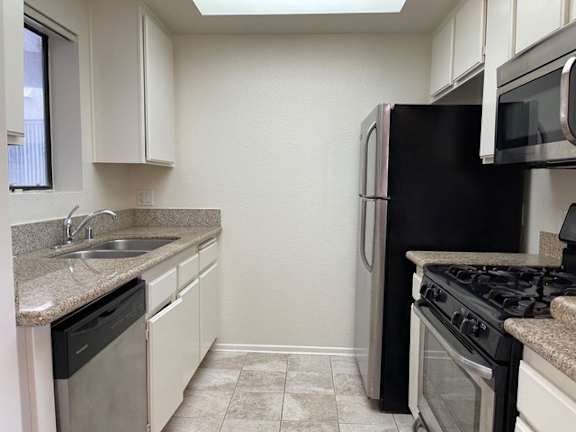 A kitchen with black appliances and white cabinets.