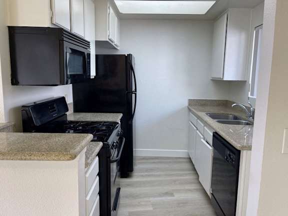 A kitchen with black appliances and white cabinets.