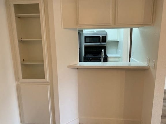 A kitchen with white cabinets and a microwave oven.
