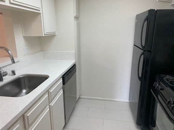 A black refrigerator sits next to a sink in a kitchen.