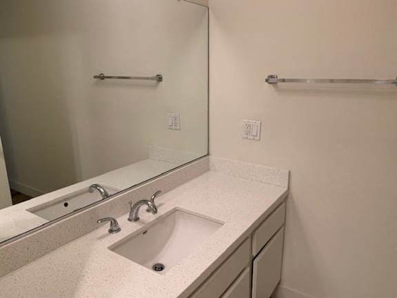 A bathroom with a sink, mirror, and towel rack.