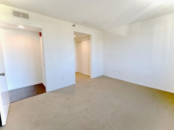 A spacious room with white walls and a closed door on the left.