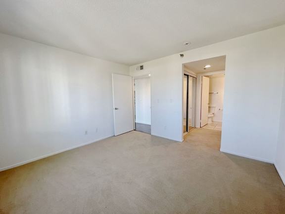 A large, empty room with a carpeted floor and white walls.