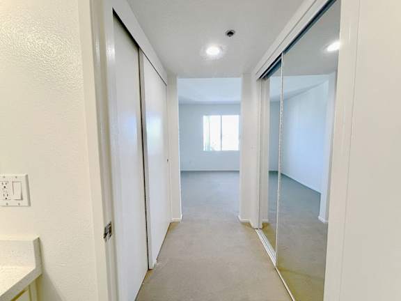 A hallway with a white door and a mirror on the wall.