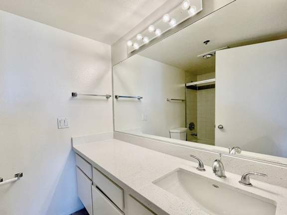 A bathroom with a white sink and a mirror above it.