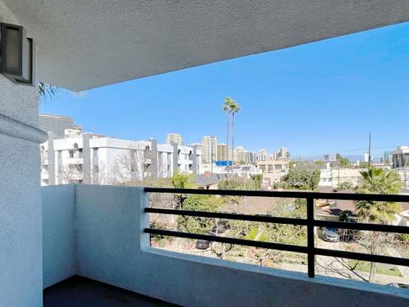 A balcony overlooks a cityscape with buildings and palm trees.