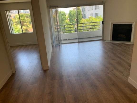 A room with wooden floors and a fireplace with a balcony outside.