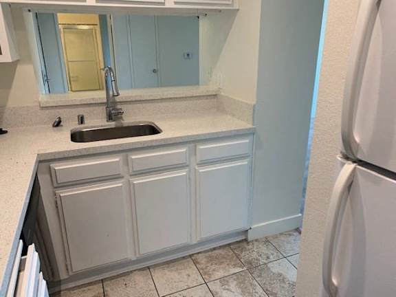A kitchen with a sink and a refrigerator.