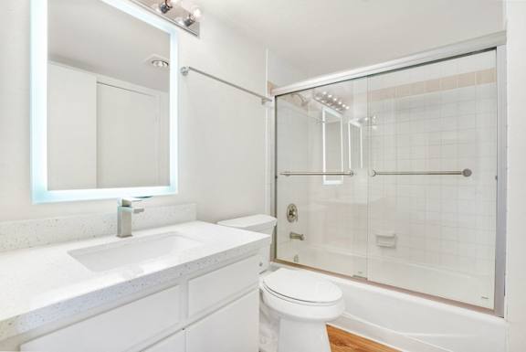 A white bathroom with a toilet, sink, and shower.