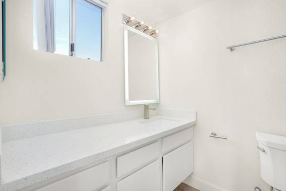A white bathroom with a large mirror and a white tub.