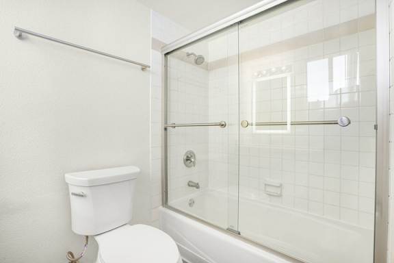 A white toilet is next to a glass shower door.