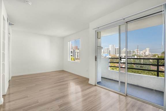 A room with a sliding glass door leading to a balcony with a view of the city.