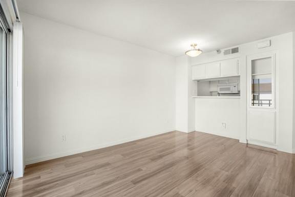 A room with a kitchenette and a window with blinds.