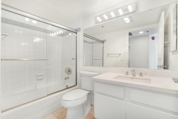 A white bathroom with a toilet, sink, and mirror.