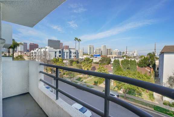 A balcony overlooks a cityscape with buildings and palm trees.