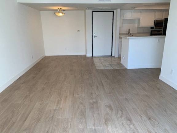 A room with a white door and a kitchen area in the background.