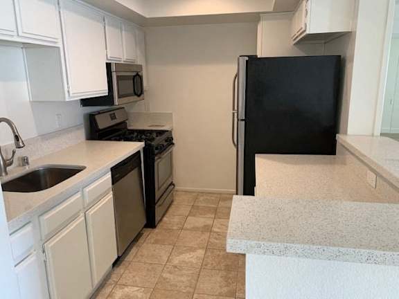 A kitchen with black appliances and white cabinets.
