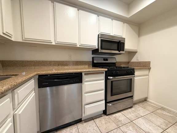 A kitchen with white cabinets and a granite countertop.