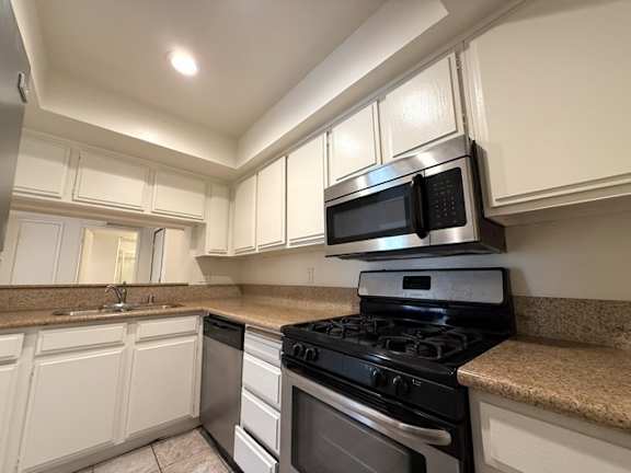 A kitchen with black appliances and white cabinets.
