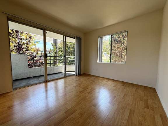 A room with wooden flooring and a window showing trees outside.