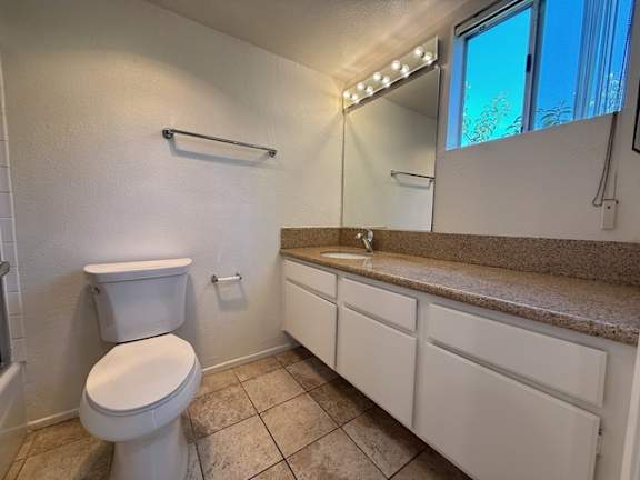 A white toilet in a bathroom with a counter and a mirror.