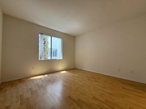 A room with a window and wooden flooring.