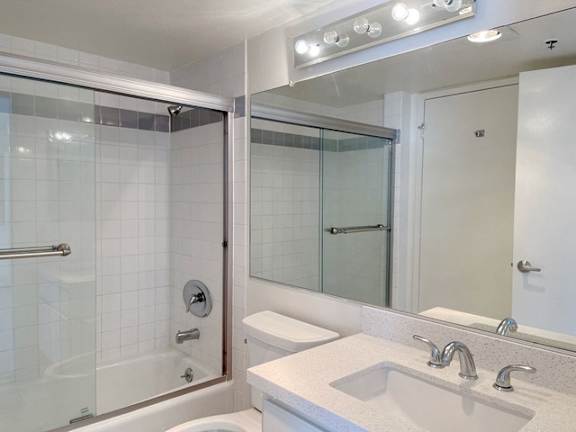 A white bathroom with a glass shower door and a white sink.
