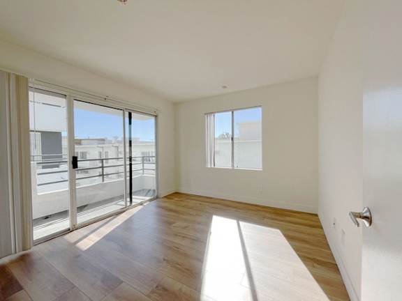 A room with a sliding glass door leading to a balcony.