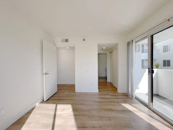 A long hallway with a rug on the floor and a glass door on the right.