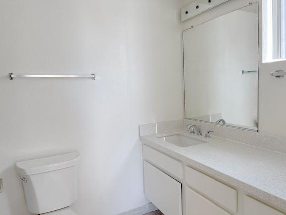 A white bathroom with a toilet, sink and mirror.