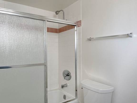 A white toilet is in a bathroom with a glass shower door.