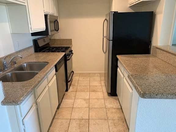 A kitchen with black appliances and white cabinets.