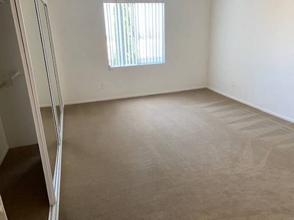 A room with a carpeted floor and a window with blinds.