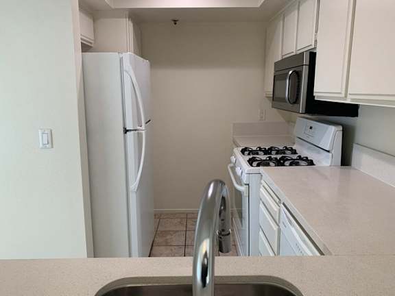 A kitchen with a white refrigerator, stove, and microwave.
