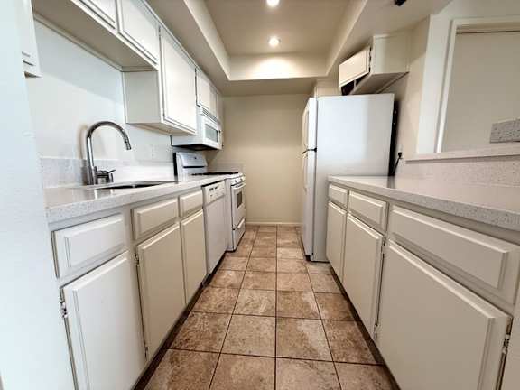 A kitchen with white cabinets and a tiled floor.