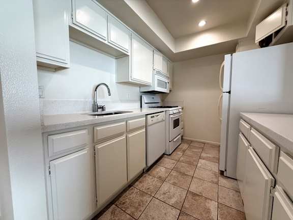 A kitchen with white appliances and cabinets.