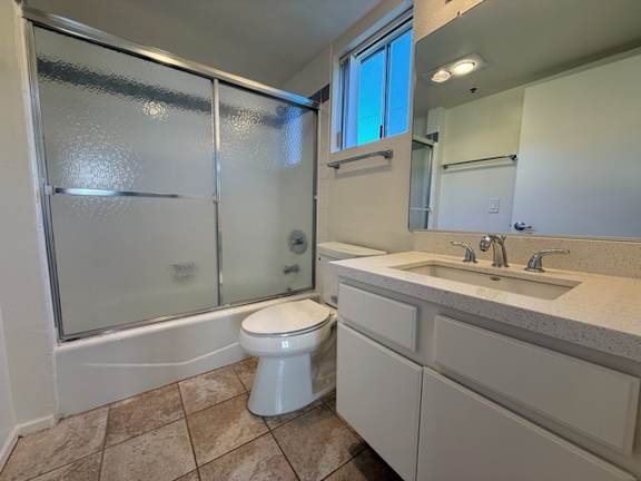 A white toilet sits in a bathroom with a walk-in shower.