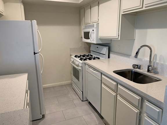A kitchen with a white refrigerator, microwave, and stove.