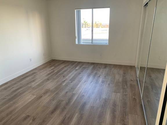 A room with wooden flooring and a window overlooking a street.