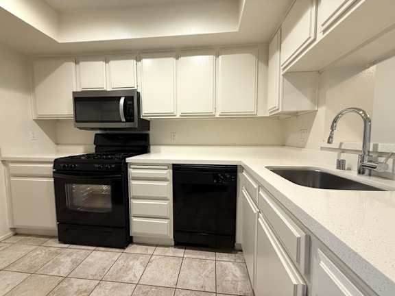 A kitchen with black appliances and white cabinets.