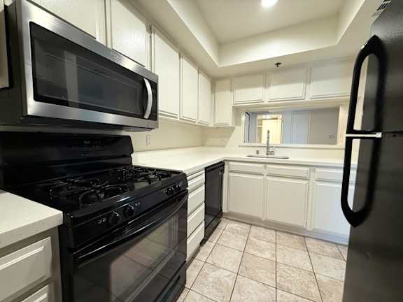A black microwave oven is on top of a black gas stove.