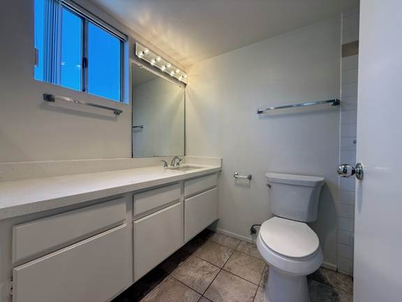 A white bathroom with a toilet, sink, and mirror.