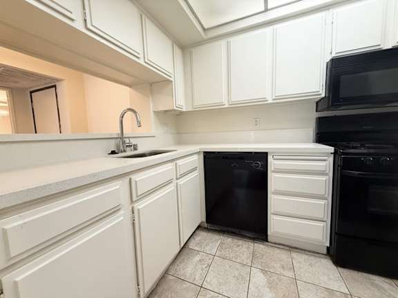 A kitchen with black appliances and white cabinets.