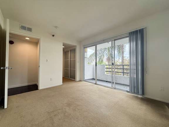 A spacious room with a sliding glass door leading to a balcony.