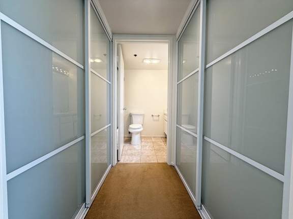 A white toilet is in the middle of a hallway.