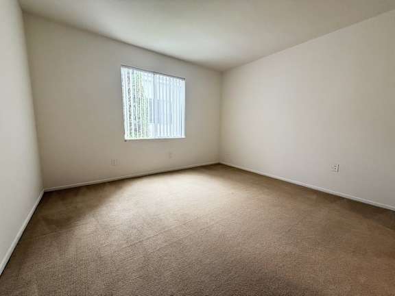 A room with a carpeted floor and a window with blinds.