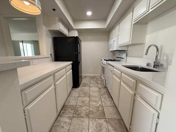 A kitchen with white cabinets and a black refrigerator.