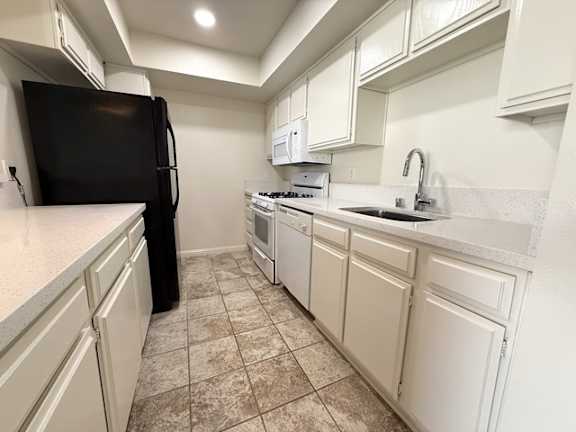 A kitchen with black appliances and white cabinets.